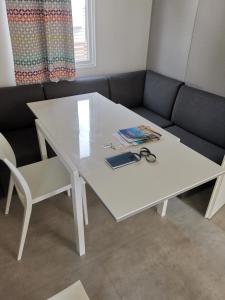 a white table and a couch with a table and a pair of scissors at Mobil home climatisé chez Mickaël et Laëtitia in Narbonne