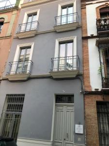 un edificio gris con ventanas y una puerta en Sevilla Home Center Suites en Sevilla