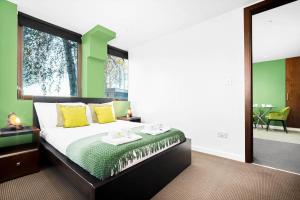 a bedroom with a bed with yellow and green accents at Modern 1 Bed Apartment in Perry Barr ☆ Close to town ✪ Next to Alexander Stadium → FREE NEARBY STREET PARKING - Easy Bus & Train Routes to City Centre - SMART TV - Located by One Stop Shopping Centre with Nandos, Argos, KFC, JD Sports and more! in Birmingham