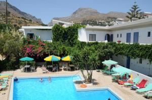 a swimming pool with chairs and umbrellas and a resort at Costas & Chrysoula in Plakias