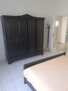 a bedroom with a bed and a black cabinet at Villa S+3 Bien Equipée à 200m de la plage in Hammamet