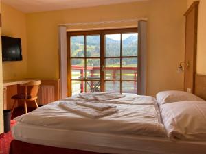 a bed in a room with a large window at Landhotel Alte Post in Oberstaufen