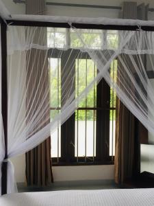 - une chambre avec un lit et une fenêtre avec des rideaux dans l'établissement Anthony Guesthouse, à Hikkaduwa