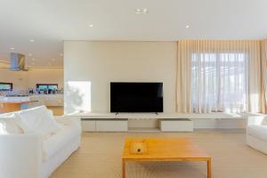 uma sala de estar com um sofá branco e uma televisão de ecrã plano em SA09 Excelente Casa 5 Suítes - Reserva Sauipe em Mata de São João