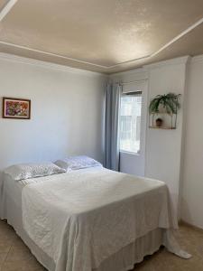 a bedroom with a bed with a white bedspread and a window at Apart Ponta Verde in Maceió