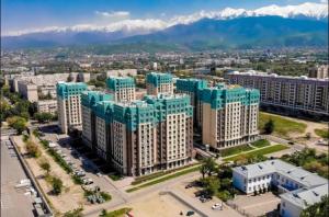 una vista aérea de un gran edificio con montañas en el fondo en Halal Apart Hotel Almaty en Almaty