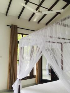 a bedroom with a bed with white mosquito netting at Anthony Guesthouse in Hikkaduwa