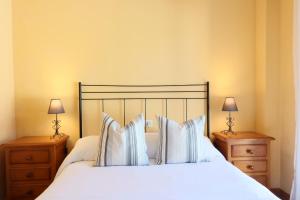 a bedroom with a bed with white sheets and pillows at Casa La Buganvilla 2 Aracena in Aracena