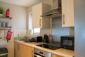 a kitchen with a sink and a stove top oven at Modern Two Bedroom Apartment with Free Parking, Wifi & Sky TV by HP Accommodation in Milton Keynes