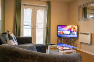 a living room with two couches and a flat screen tv at Modern Two Bedroom Apartment with Free Parking, Wifi & Sky TV by HP Accommodation in Milton Keynes