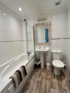 a bathroom with a tub and a toilet and a sink at The Coastal Escape in Bournemouth