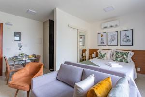 ein Schlafzimmer mit einem Bett, einem Sofa und einem Tisch in der Unterkunft Kit Net Studio - II, moderna e aconchegante in Brasilia