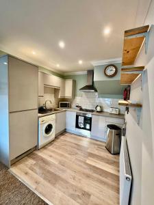 una cocina con gabinetes blancos y una lavadora y secadora en The Coastal Escape, en Bournemouth