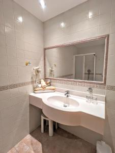 ein weißes Badezimmer mit einem Waschbecken und einem Spiegel in der Unterkunft Hotel Heinz in Bruneck