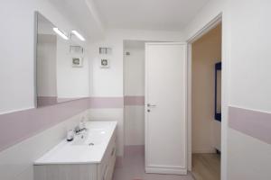 Un baño blanco con lavabo y espejo. en Porta San Giovanni Suite, en Roma 11 fotos más