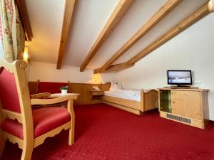 a room with a bed and a tv and a chair at Hotel Heinz in Brunico