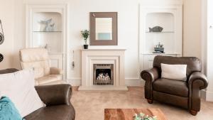 a living room with two chairs and a fireplace at At Anchor (with a Harbour View) in Fife