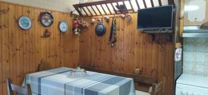 a dining room with a table and a tv on a wooden wall at Casa di Lucy in Frabosa Soprana