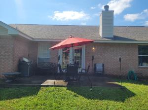 a house with a patio with a red umbrella at Bedroom Four minutes from beach in Pensacola