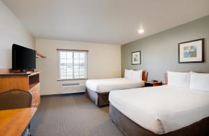 a hotel room with two beds and a flat screen tv at WoodSpring Suites Chesapeake-Norfolk Greenbrier in Chesapeake
