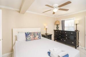 1 dormitorio con cama blanca y ventilador de techo en Oceans 13 Unit A en Saint Augustine Beach