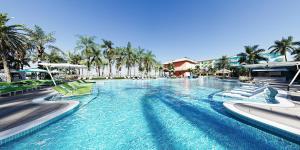フォートマイヤーズビーチにあるMargaritaville Beach Resort Ft Myers Beachのヤシの木と椅子が備わるリゾートのプールを利用できます。