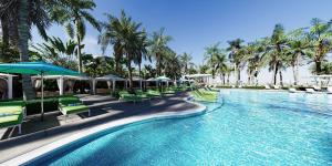 una piscina con sillas, sombrillas y palmeras en Margaritaville Beach Resort Ft Myers Beach, en Fort Myers Beach