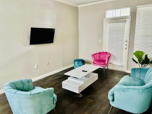 a living room with two chairs and a table and a tv at Heartbeat Of ATL- Gated Community, Pool, Gym, and much more! in Atlanta
