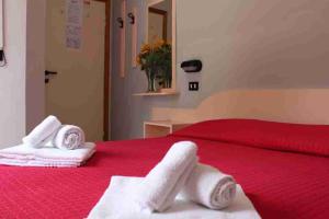 1 dormitorio con toallas en una cama roja en Hotel Laura Beach en Rímini