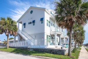 a white house with palm trees in front of it at Oceans 13 Condo D in Saint Augustine Beach