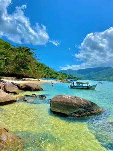 a boat in the water next to a beach at Pousada Chalés Cantinho do Ronca - Paraty Mirim in Paraty