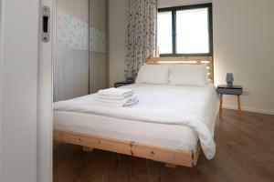 a bedroom with a bed with white sheets and a window at Seaside Court Retreat By IsrApart in Tel Aviv