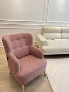 una silla y un sofá en la sala de estar en French Style Comfy Homestay Alor Setar 现代极简法式温馨民宿, en Alor Setar