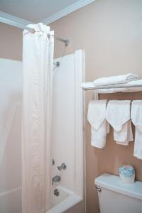 y baño con ducha, aseo y toallas. en Super 8 by Wyndham Columbia/Ft. Jackson SC, en Columbia