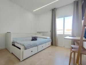 a white bedroom with a bed and a window at Apartamentos Bello Lanzarote in Arrecife