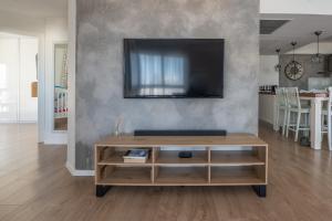 a living room with a tv and a wooden coffee table at Seaside Court Retreat By IsrApart in Tel Aviv