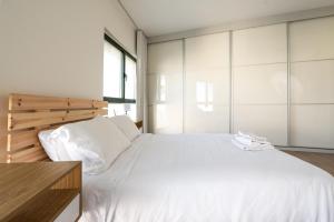 a bedroom with a large bed with white sheets at Seaside Court Retreat By IsrApart in Tel Aviv