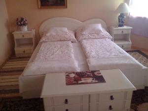 ein weißes Bett mit zwei Kissen und einem Tisch in der Unterkunft Marina-Bük Apartmanház in Bük