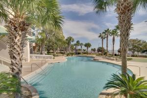 a swimming pool with palm trees in a resort at 6th-Floor Gulfport Condo with Views Walk to Beach in Gulfport