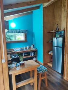cocina con paredes azules, mesa y nevera en Cabañas Rayén en parcela, adosada y con estacionamiento privado en Pelluco, en Puerto Montt