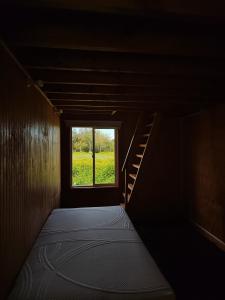 Habitación oscura con cama y ventana en Cabañas Rayén en parcela, adosada y con estacionamiento privado en Pelluco, en Puerto Montt