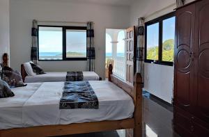 two beds in a room with a view of the ocean at Villea Frangipani in Mahe