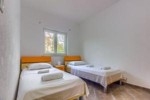 two twin beds in a room with a window at Apartmani Mato in Pirovac