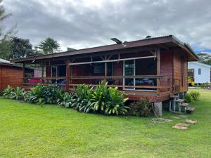 une grande maison en bois avec une pelouse dans l'établissement HEIRAI TAHITI EXPERIENCE, à Vairao