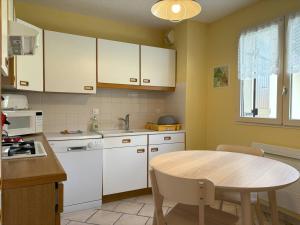 a kitchen with white cabinets and a wooden table at Appartement Villard-de-Lans, 3 pièces, 6 personnes - FR-1-548-4 in Villard-de-Lans