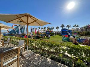 a playground with an umbrella and a park with slides at Salty life chalet, a two bedroom apartment by the swimming pool at Azha - Ain Sokhna - selected in the top 20 rentals to stay at in Sokhna in Ain Sokhna