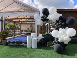 Un mucchio di palloncini bianchi e neri davanti a una piscina. di צימר היעד a Dāliyat el Karmil