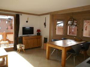 a dining room with a wooden table and a television at Appartement haut de gamme 3P cabine, pied des pistes, balcon, parking, centre station à 150m - FR-1-557-15 in Les Adrets