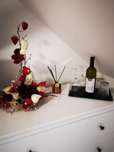 una bottiglia di vino e un vaso di fiori su un comò di ubytování U NIKY a Hodonín
