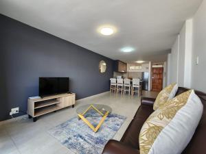 uma sala de estar com um sofá e uma televisão em Penzance by the beach em Durban